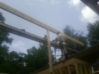 Carpenter setting a ridge beam over a new addition frame — Ice Dam Removal by Roofing Brothers in Stratham