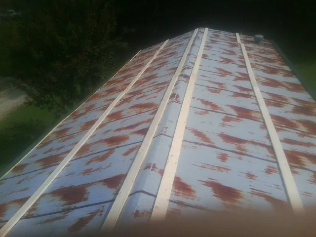Rusted metal roof panels with new wood purlins before replacement — Storm Damage Roof Repair in Stratham by Roofing Brothers