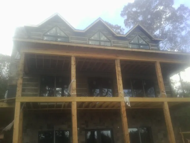 Dormers and porch framing on a large log home under construction — Roof Coating work by our crew in Stratham