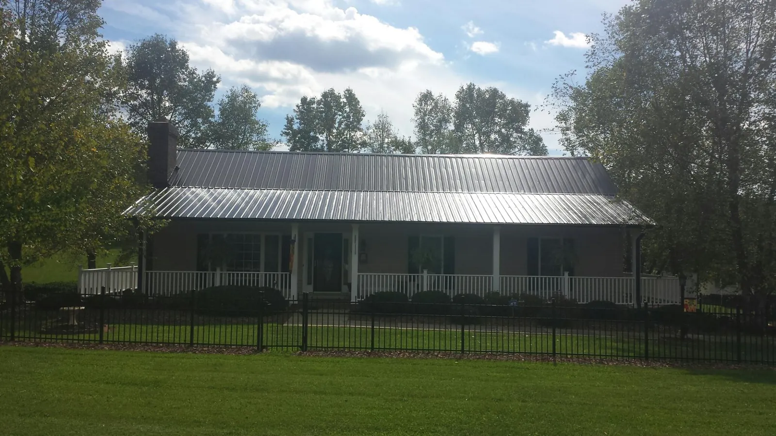 Gray metal roof on a brick ranch with a full width front porch — Gutter Guard Installation work by our crew in Stratham