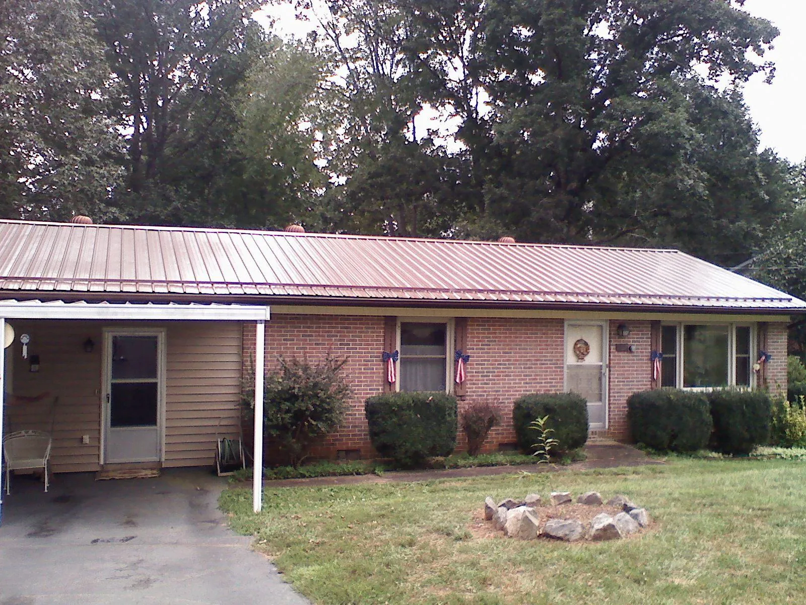 Bronze metal roof and carport on a brick ranch home — Roof Repair work by our crew in Stratham
